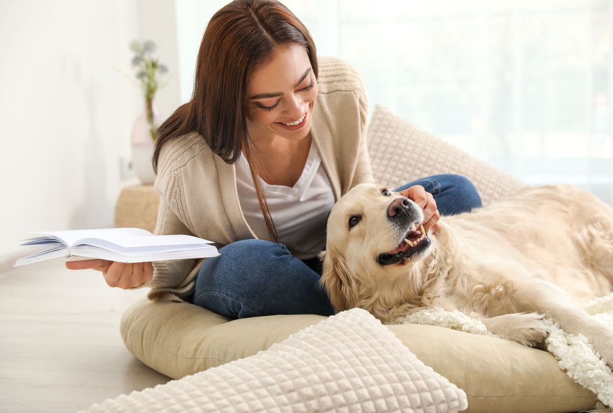Oxyfresh-pet-water-additive-to-freshen-stinky-dog-breath-picture-of-woman-holding-a-book-leaning-over-her-smiling-golden-retriever
