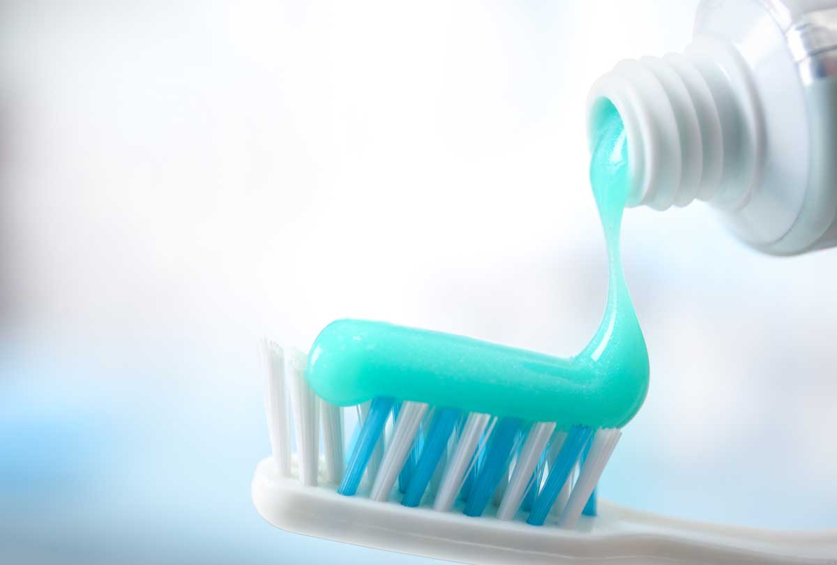 oxyfresh dental image of bright blue toothpaste squeezed out of a bottle onto a toothbrush