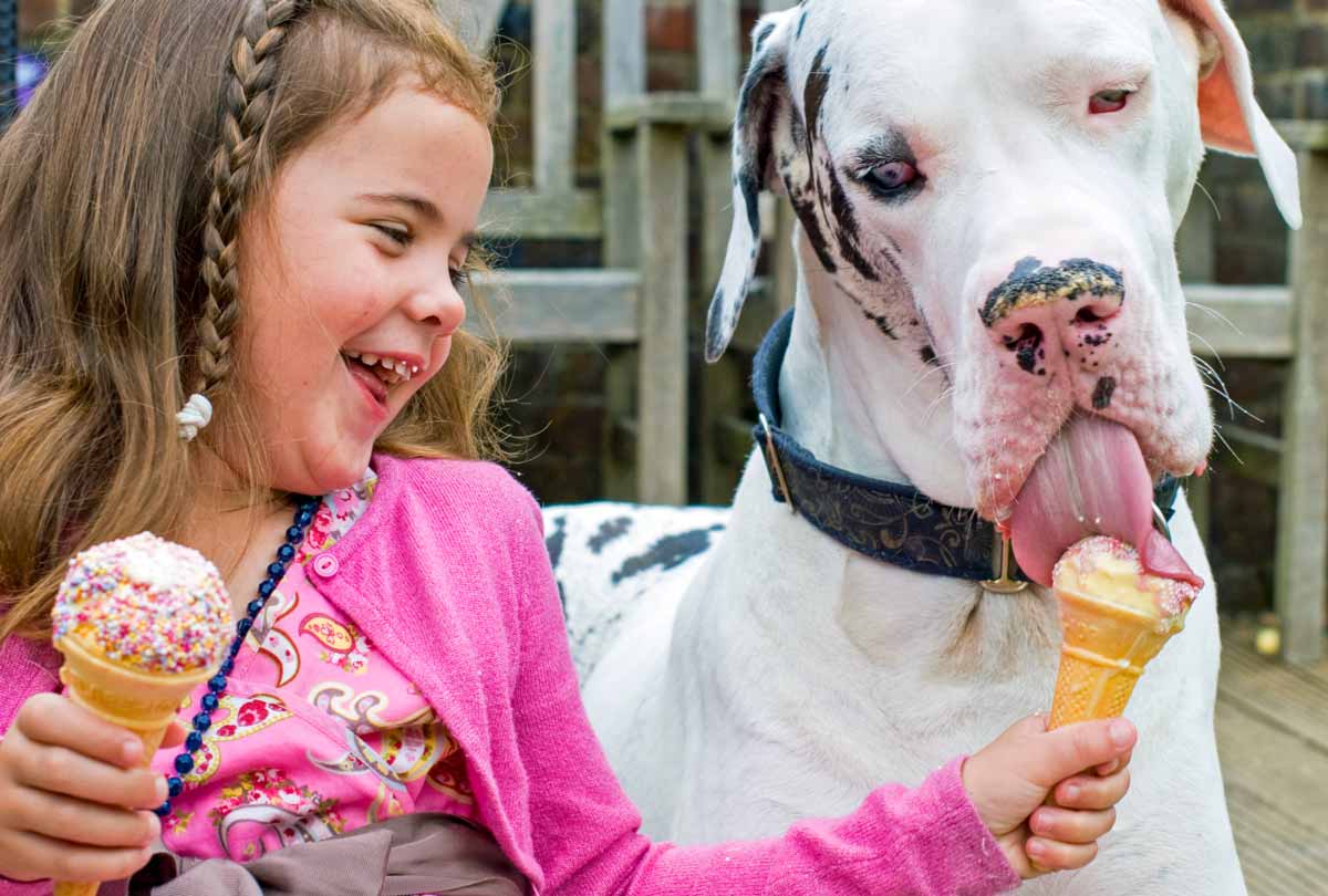 oxyfresh pet young girl smiling and laughing as she shares a lick of her ice cream cone with her pooch