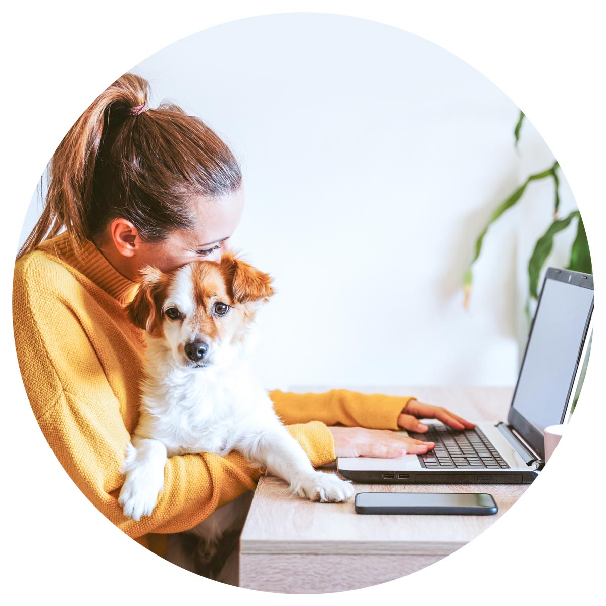girl hugging her pup as she surfs the web on her laptop
