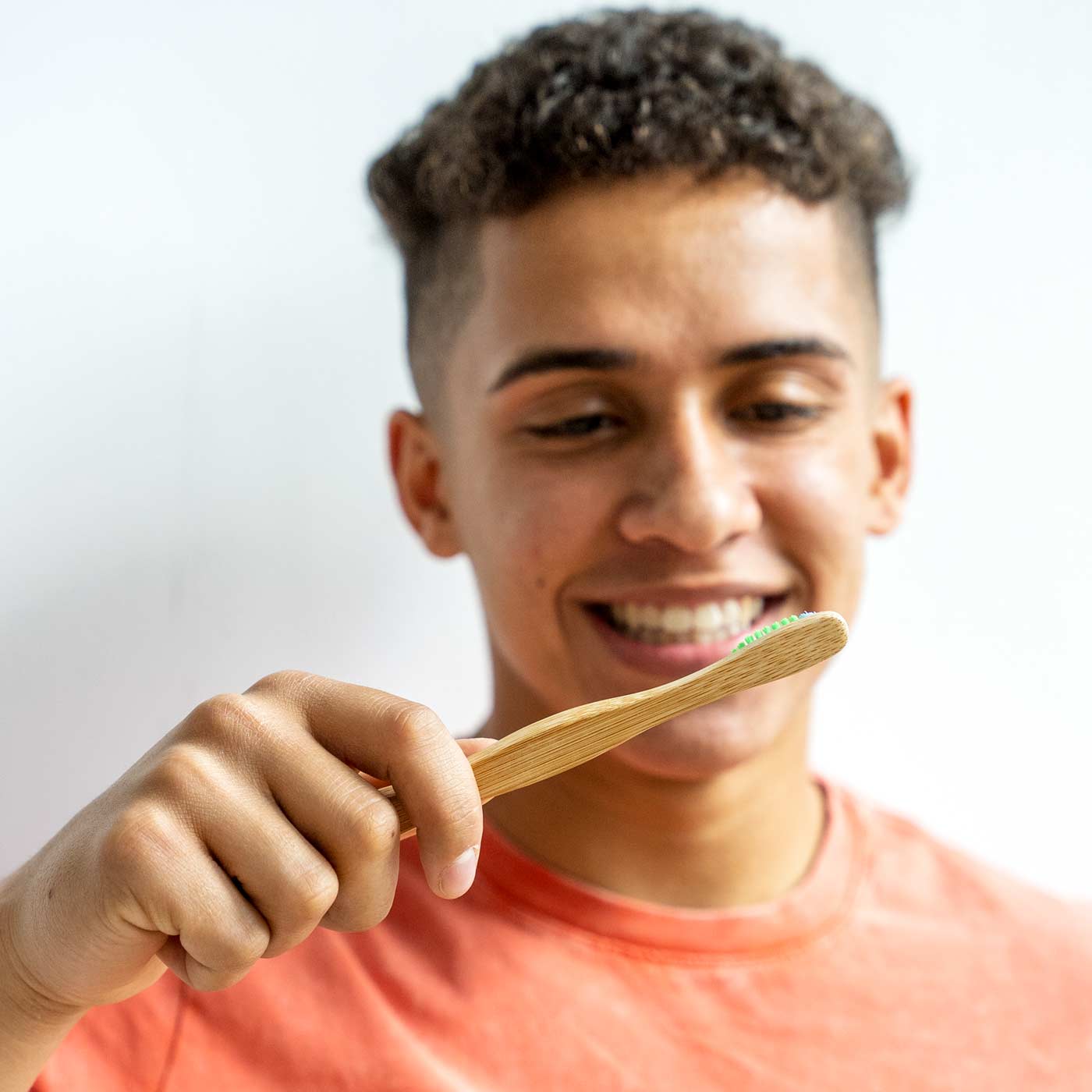 smiling young man holding oxyfresh bamboo toothbrush