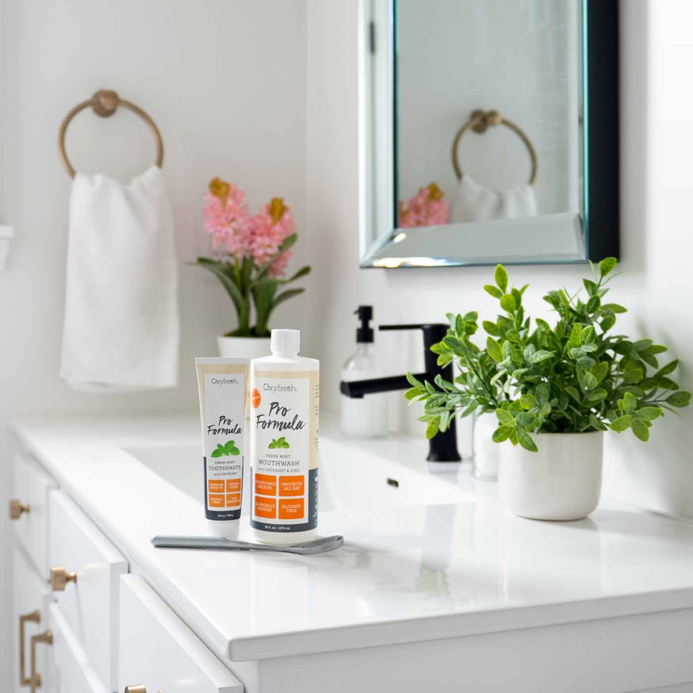 Pro-formula-system-including-pro-formula-mouthwash-with-zinc-and-freshmint-toothpaste-along-with-an-oolitt-tongue-scraper-on-countertop-in-beautiful-white-bathroom
