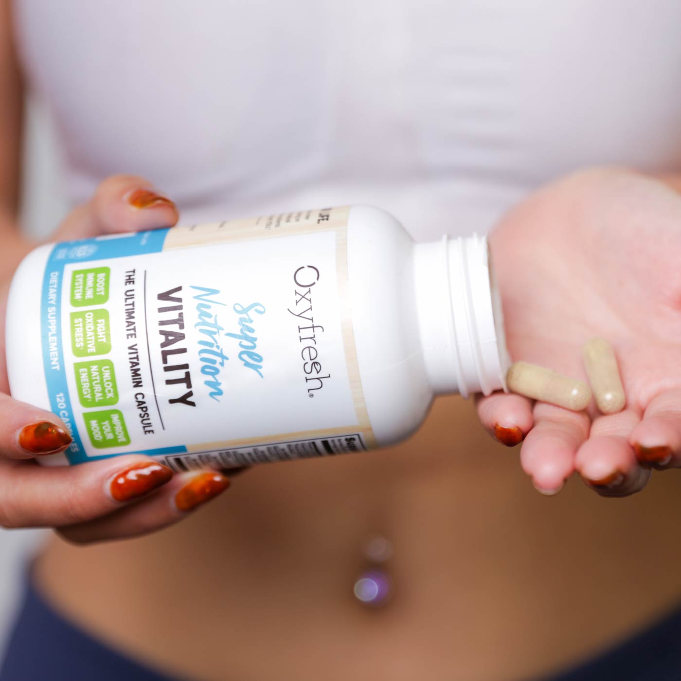Woman-in-workout-clothes-holding-bottle-of-oxyfresh-vitality-supplement-super-nutrition-vitamin-capsules