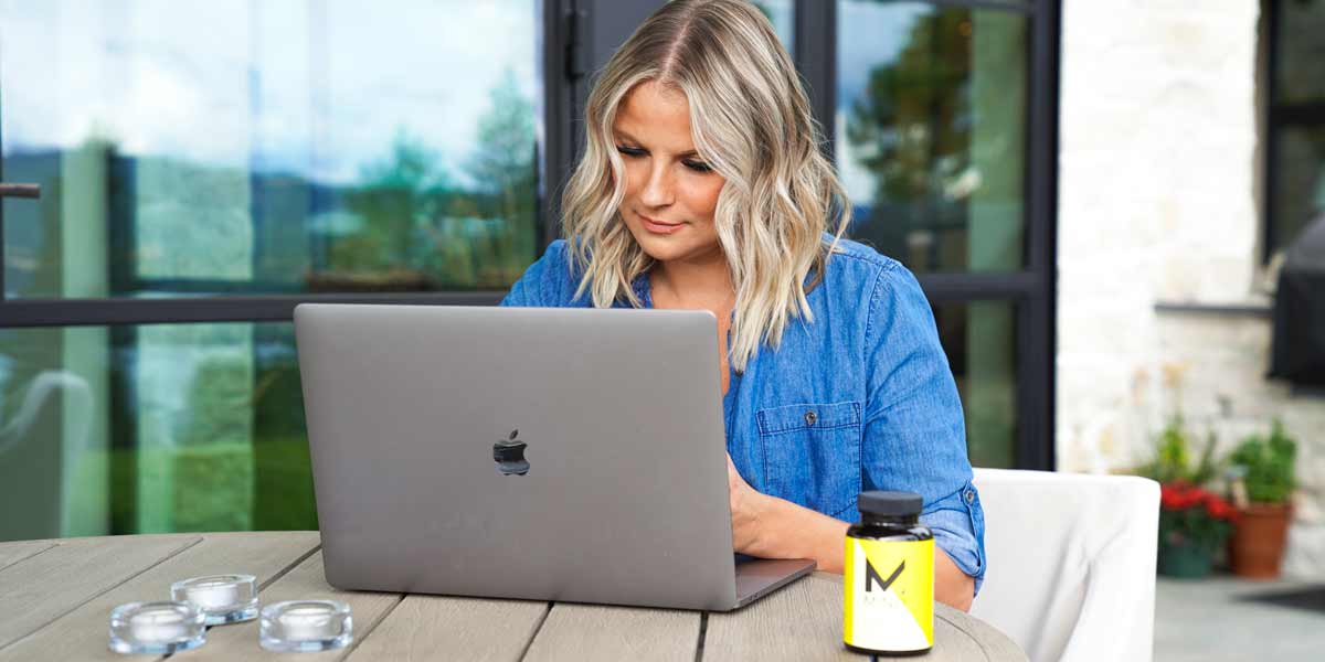 Woman-working-on-her-laptop-outside-focusing-with-a-bottle-of-oxyfresh-mind-nootropic-on-the-table-in-front-of-her