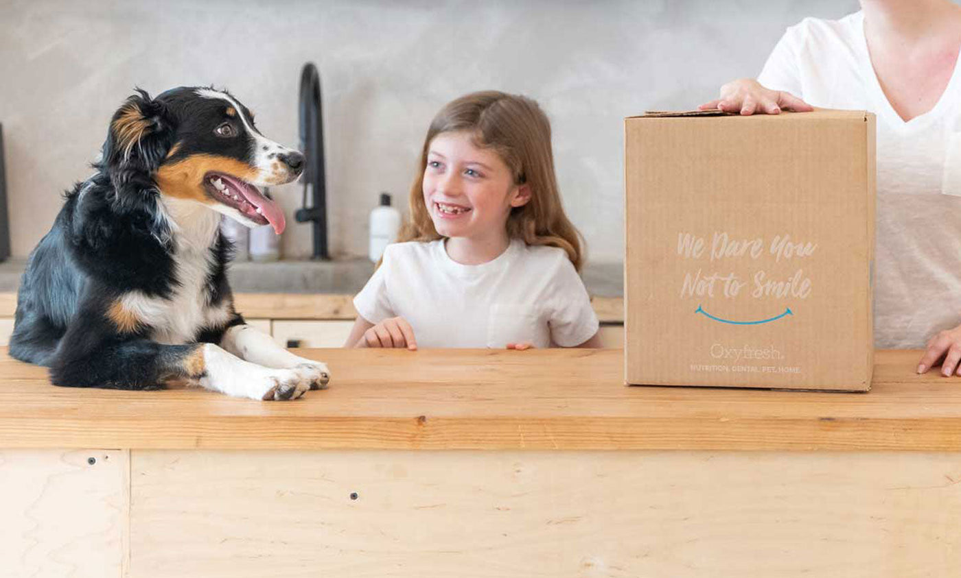 a pup, a young girl, and her mother at the counter smiling with an oxyfresh shipping box ready to be opened