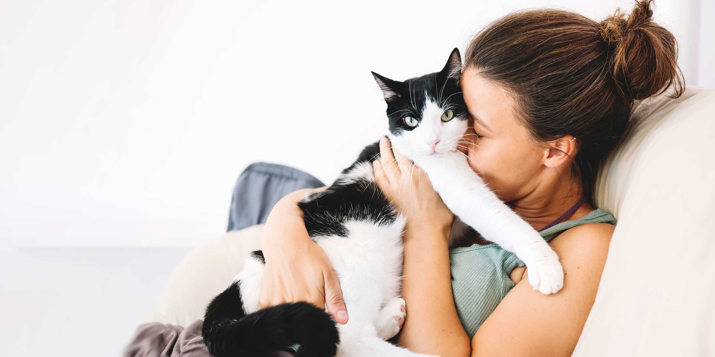 woman snuggling her cat on the couch 