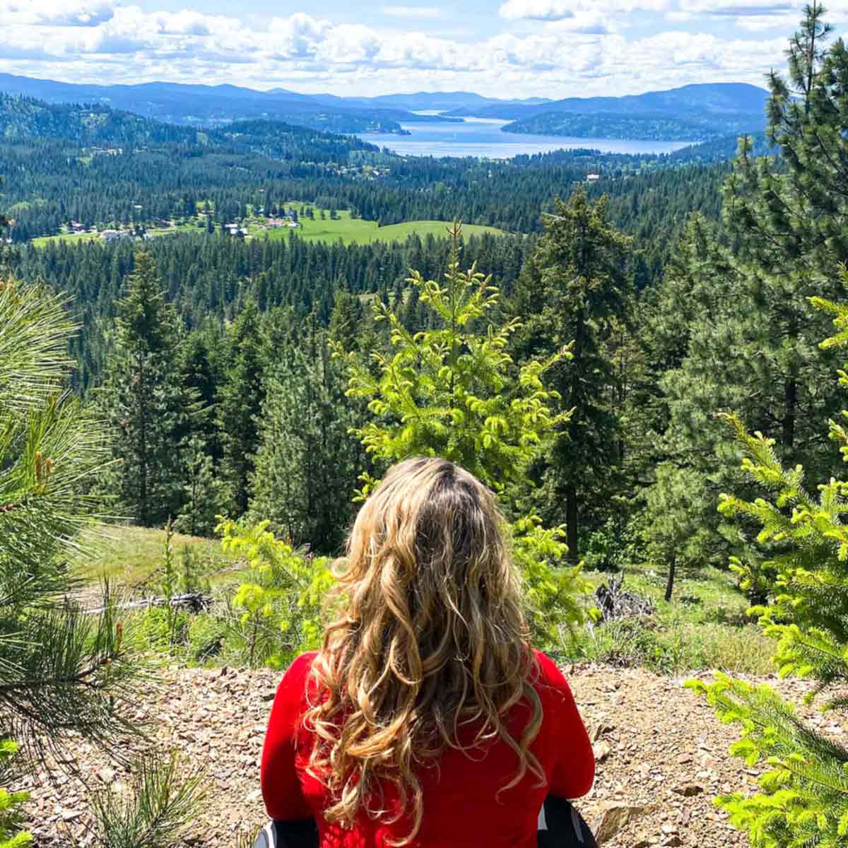woman sitting on the top of a hill admiring coeur d'alene lake