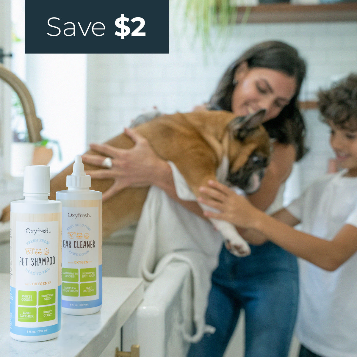 woman and her son lifting their bulldog out of the kitchen sink after a bath with oxyfresh premium squeaky clean kit containing pet shampoo and ear cleaner