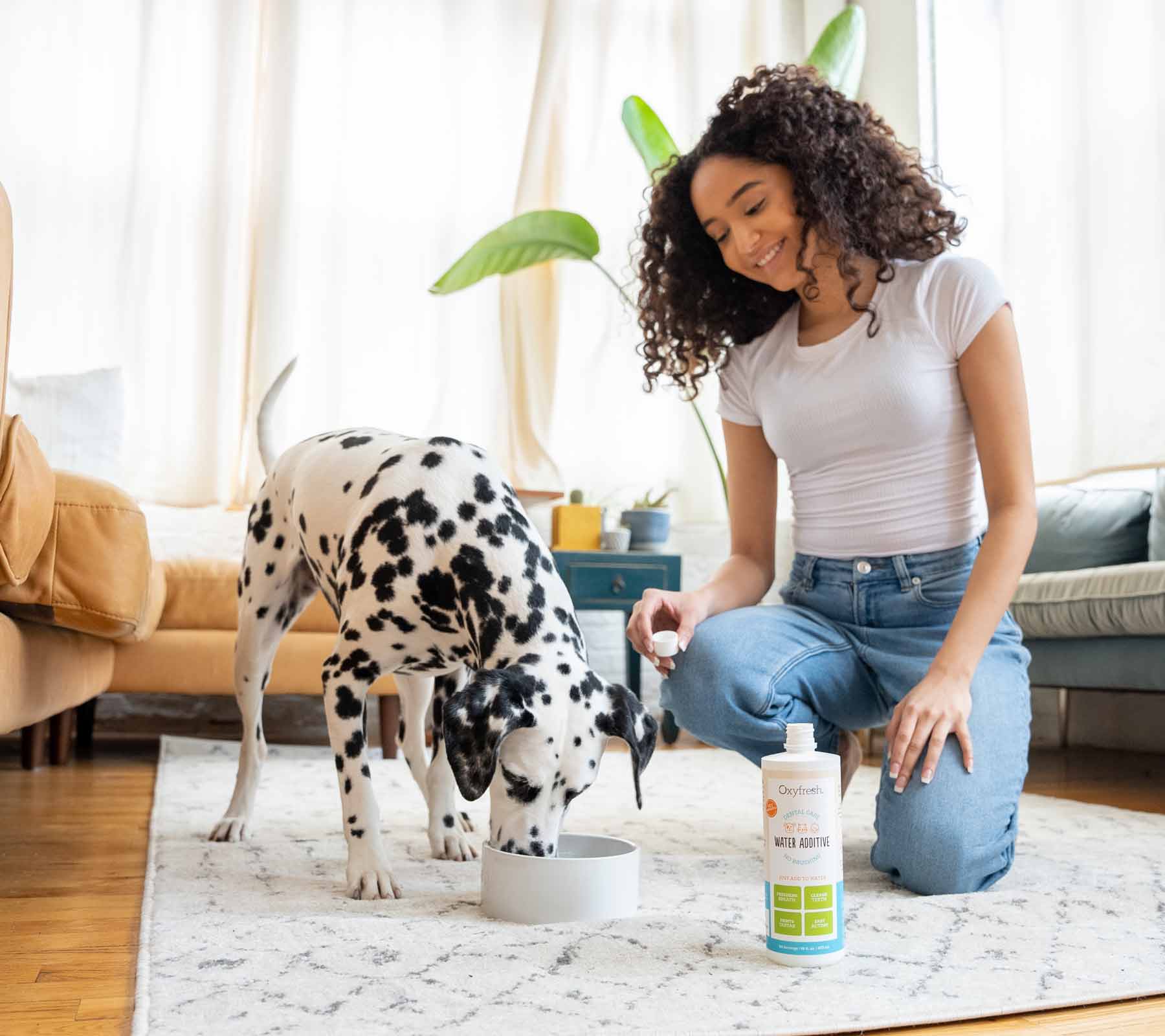 woman-and-dalmation-drinking-water-with-oxyfresh-pet-water-additive-and-water-in-living-room