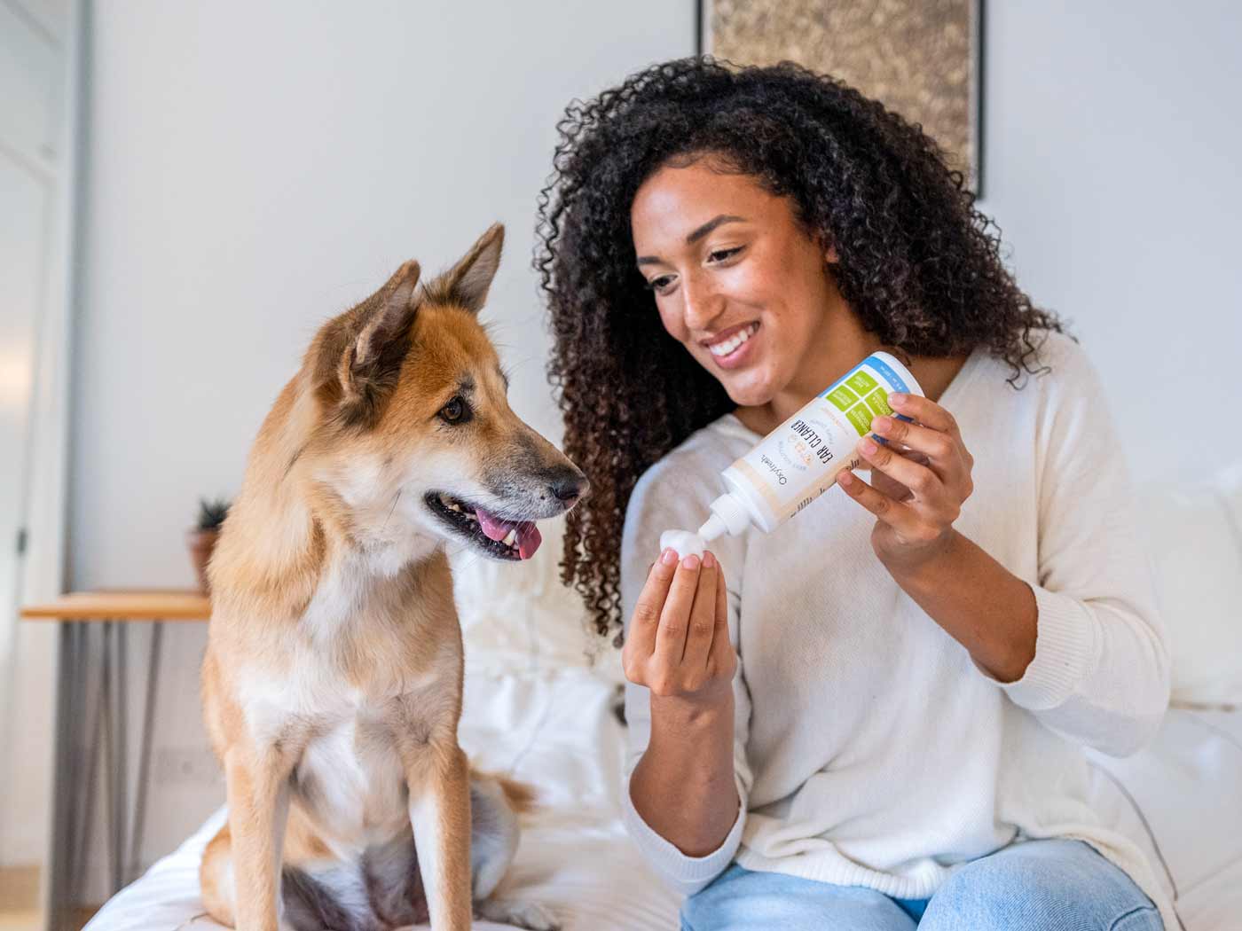 woman-smiling-applying-oxyfresh-ear-cleaner-to-a-cotton-ball-while-her-dog-looks-happily-towards-her