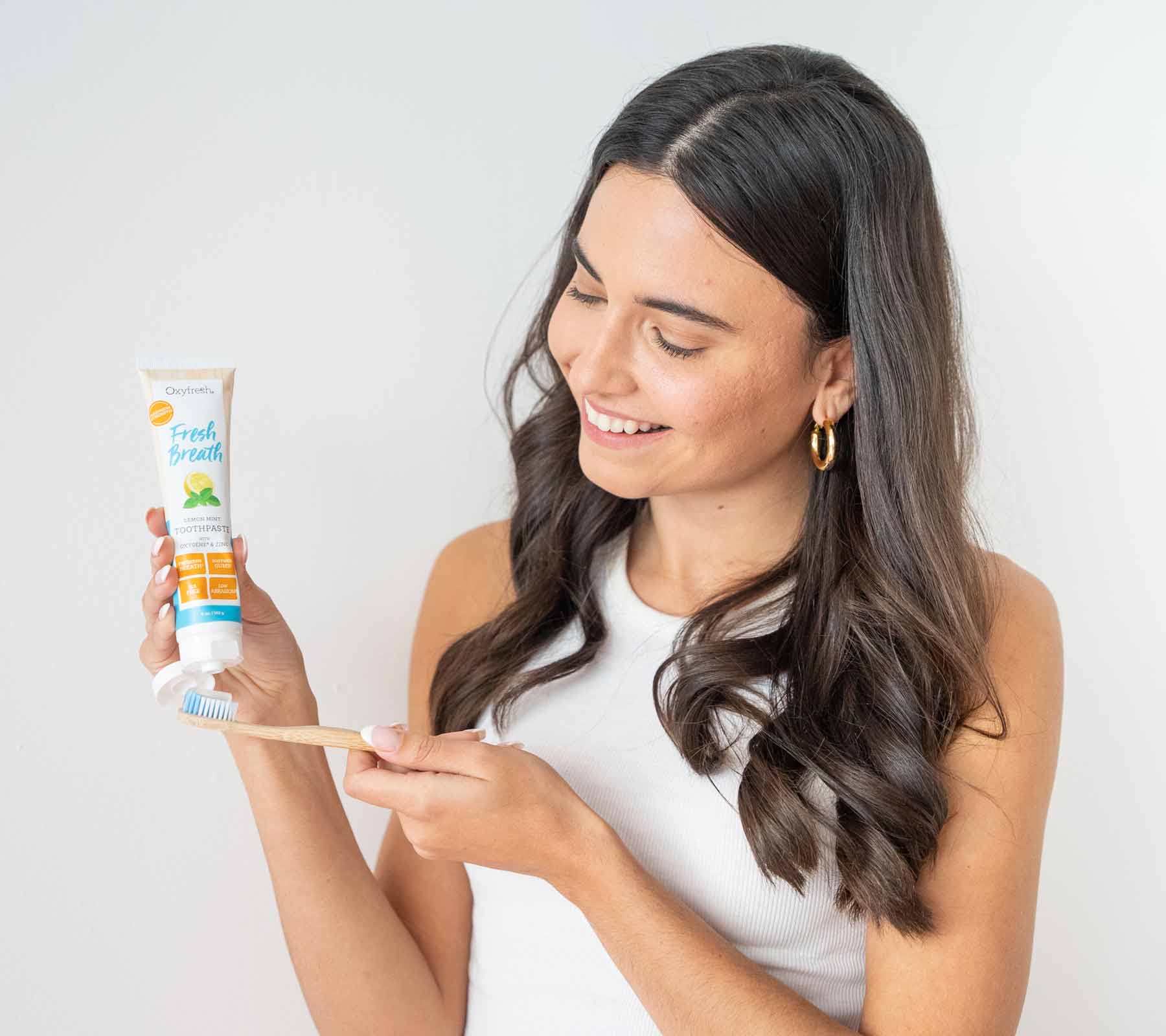 woman smiling applying oxyfresh lemon mint toothpaste to her toothbrush