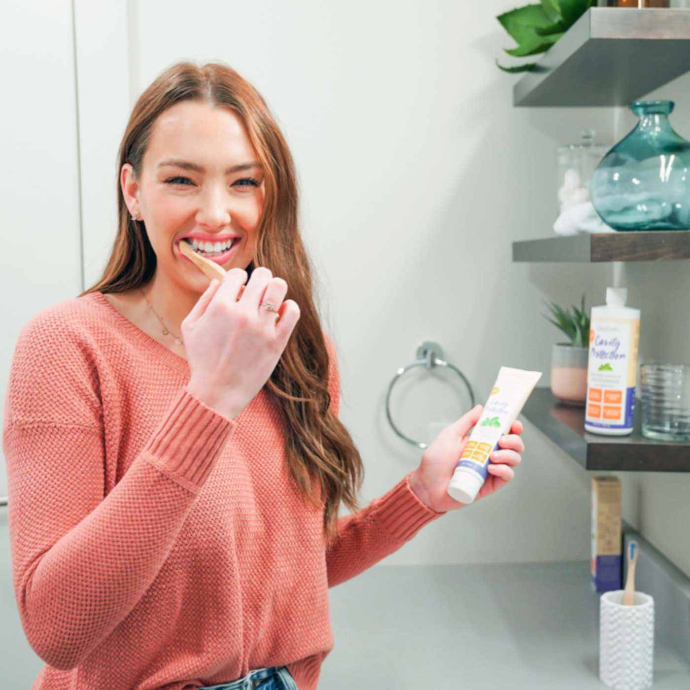 woman-smiling-while-brushing-her-teeth-with-the-oxyfresh-cavity-fighting-system-including-cavity-fighting-toothpaste-and-fluoride-mouthwash