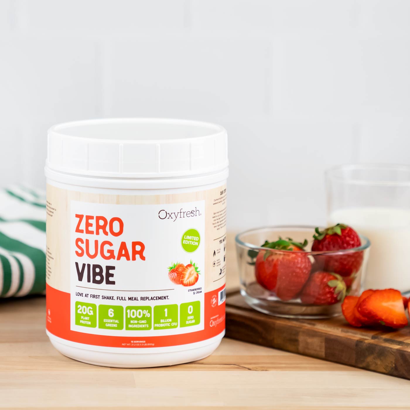 oxyfresh-vibe-zero-sugar-strawberry-protein-powder-on-the-countertop-next-to-glass-of-ice-cold-milk-and-fresh-strawaberries-on-cutting-board