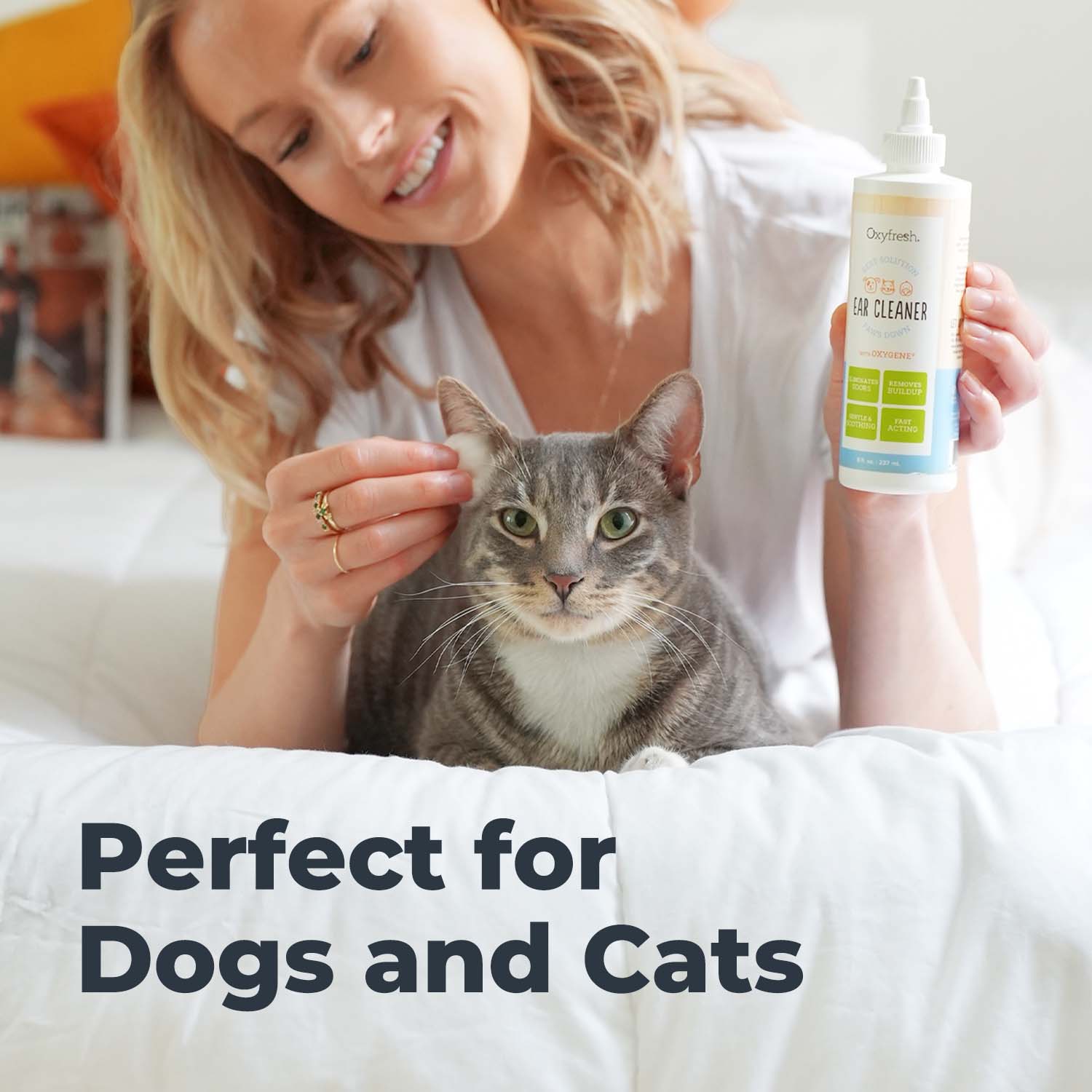 oxyfresh pet ear cleaner woman smiling using cat ear wash on a cotton ball for her cats ears with words that say perfect for dogs and cats